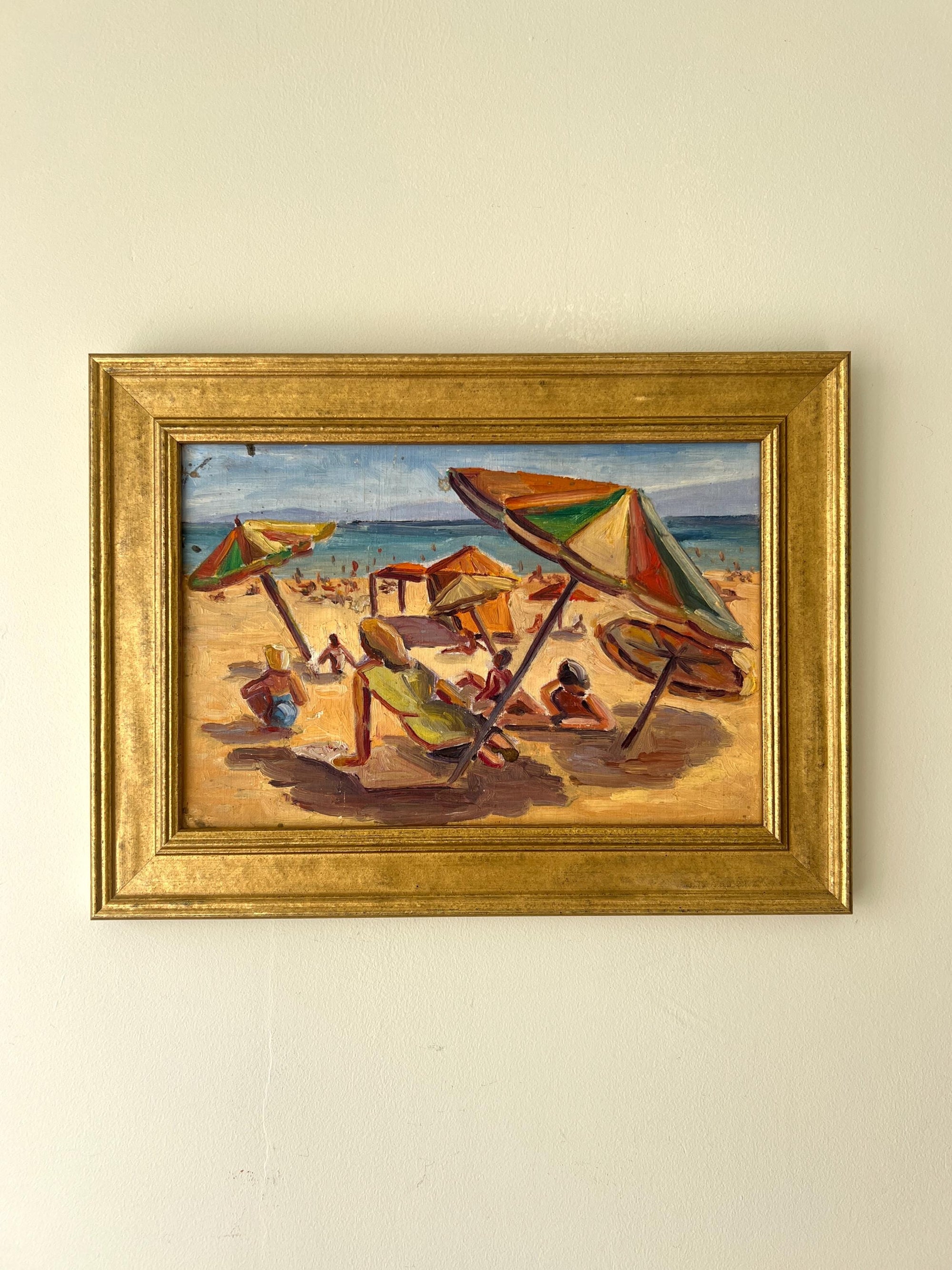 Framed vintage oil painting of a beach scene with colorful umbrellas and sunbathers, available at Hue.