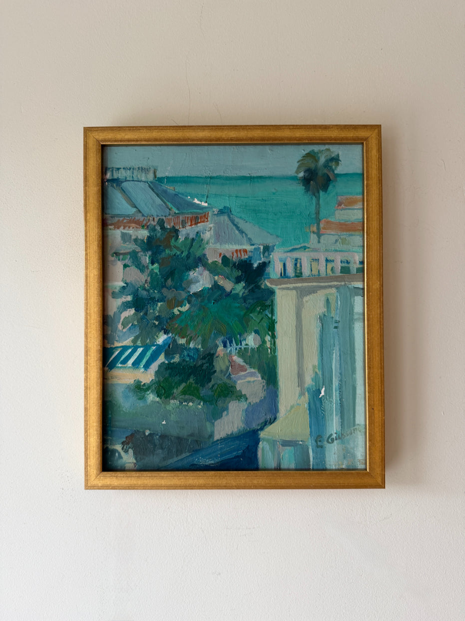 Framed vintage oil painting of a coastal scene with buildings and trees. Available at Hue. 