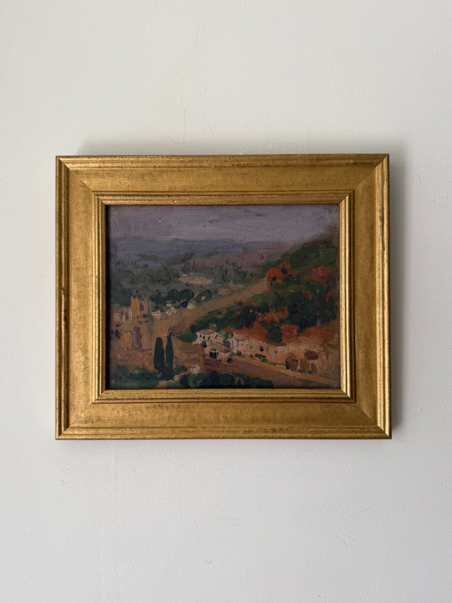 A framed vintage landscape oil painting of a hillside village with green trees and terraced hills. Available at Hue. 