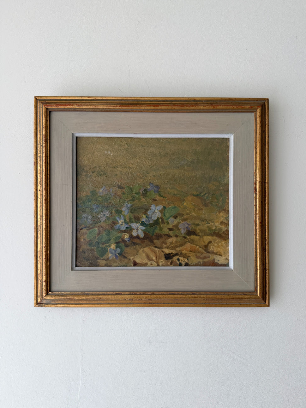 Framed vintage oil painting of blue flowers in a landscape. Available at Hue. 