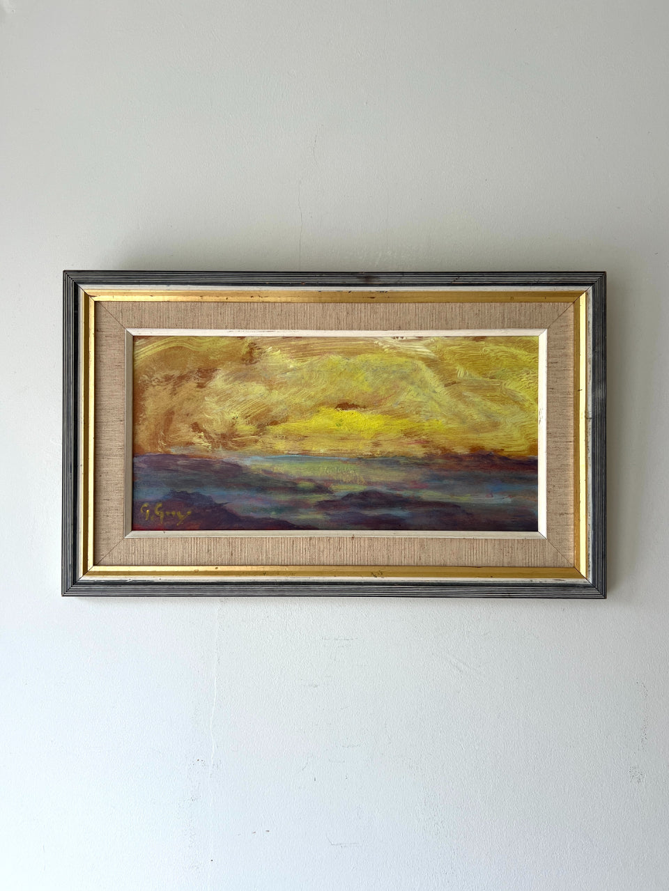 Framed vintage oil painting of a summer landscape with a  glowing yellow and orange horizon. Available at Hue.