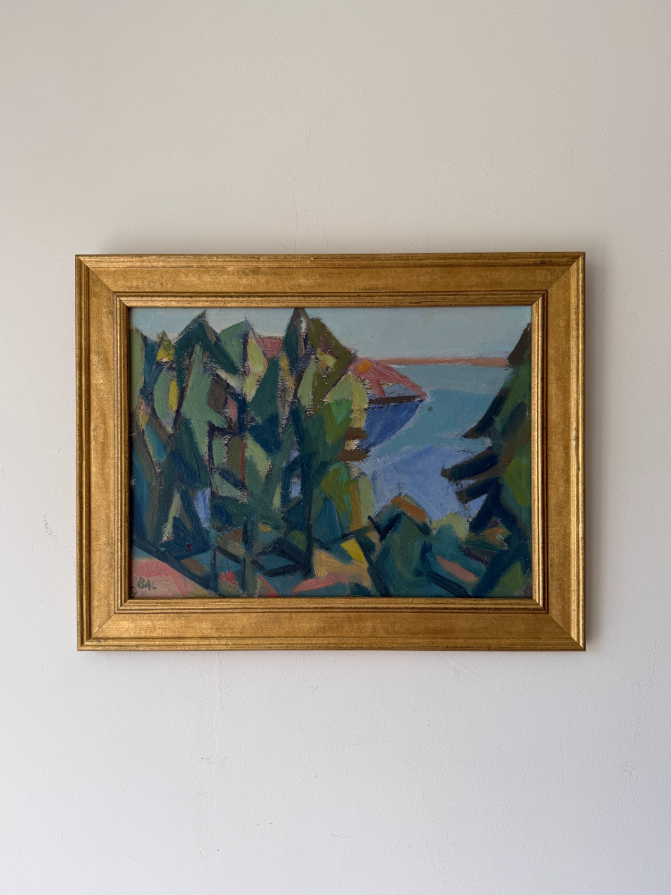 A framed vintage landscape oil painting featuring stylized green trees and blue water, enclosed in a gold frame. Available at Hue. 