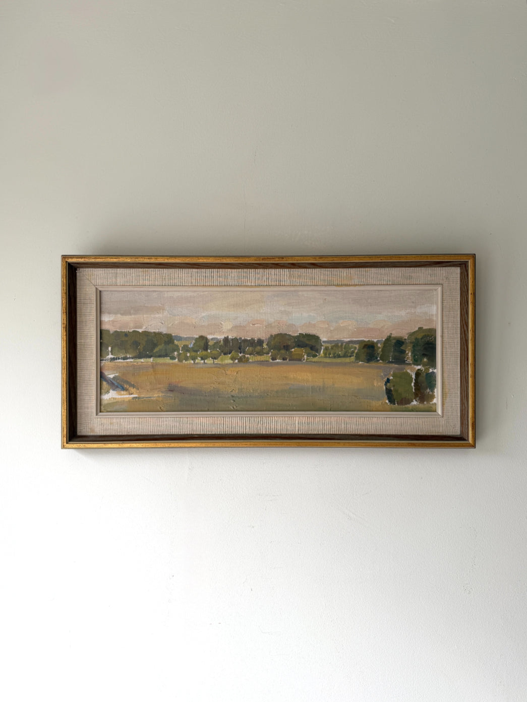 Framed vintage landscape oil painting of a rural scene with trees and fields. Available at Hue. 