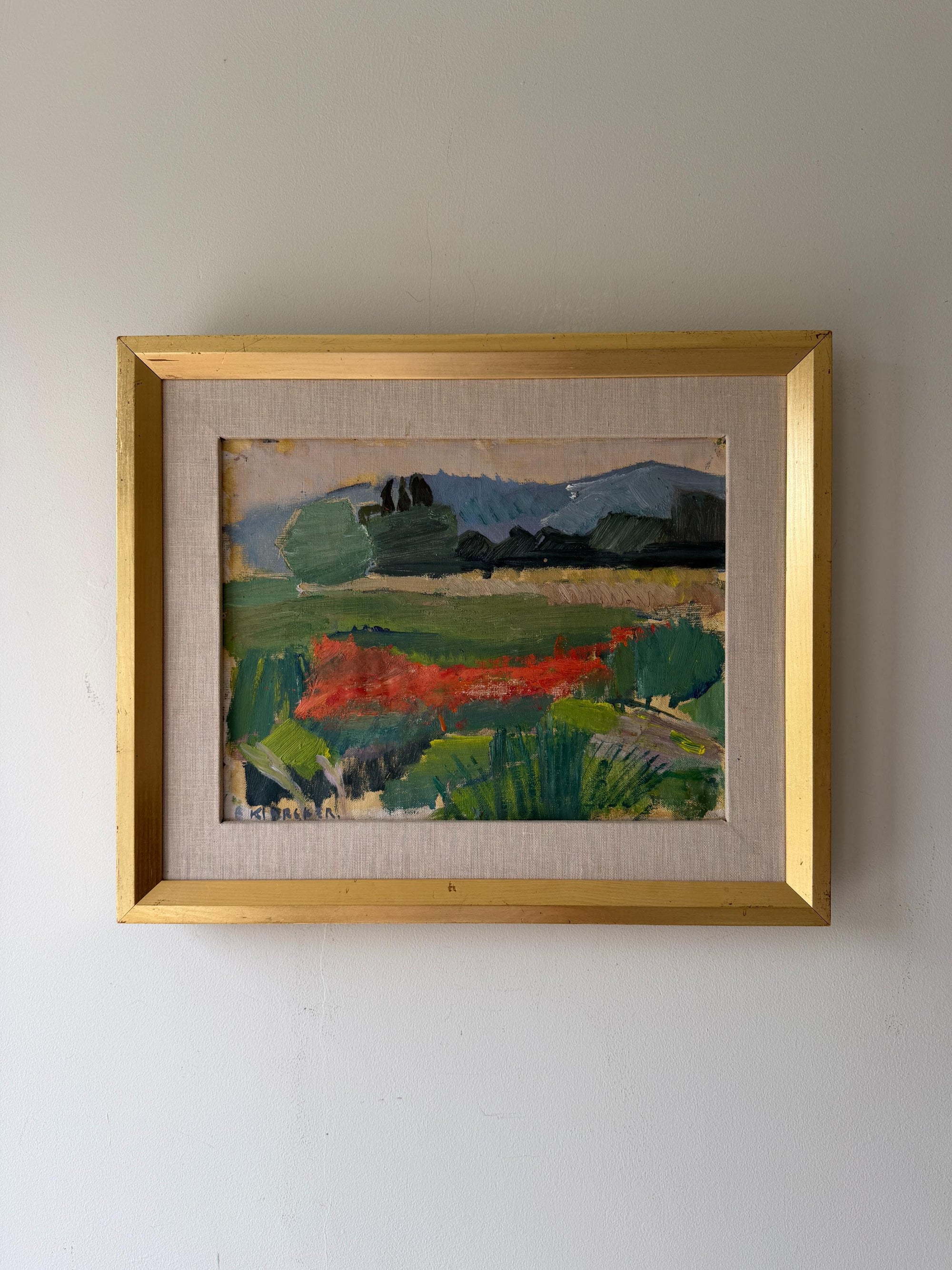 A framed vintage landscape oil painting featuring green fields, rusty red wild flowers, and blue hills. Available at Hue. 