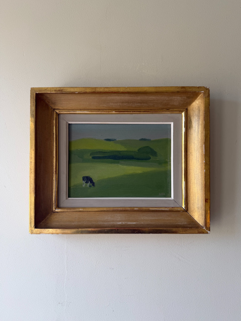 Framed vintage oil painting of a landscape with a grazing cow. Available at Hue.