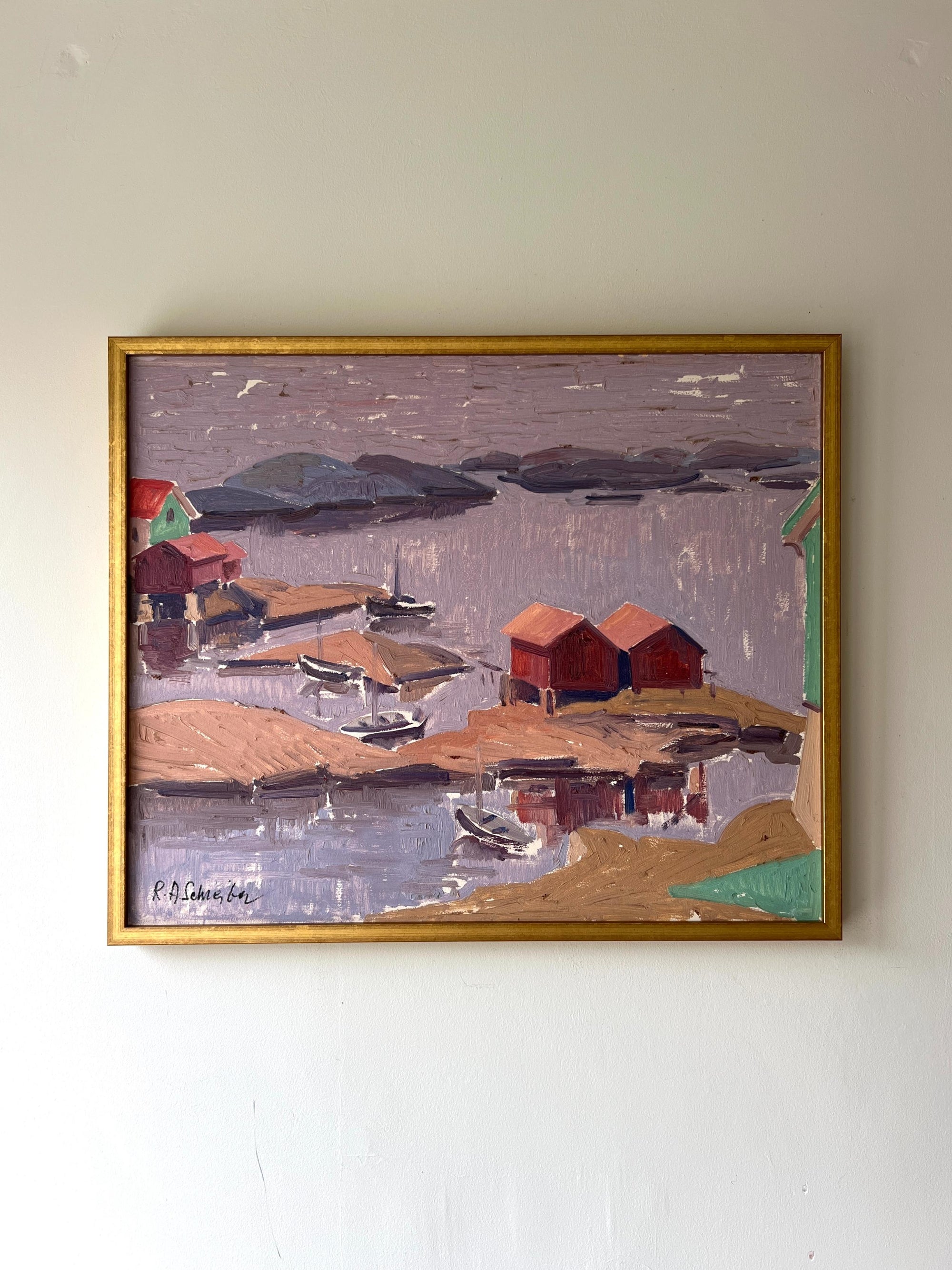A framed vintage oil painting of a tranquil harbour scene with boats and cabins. Available at Hue. 