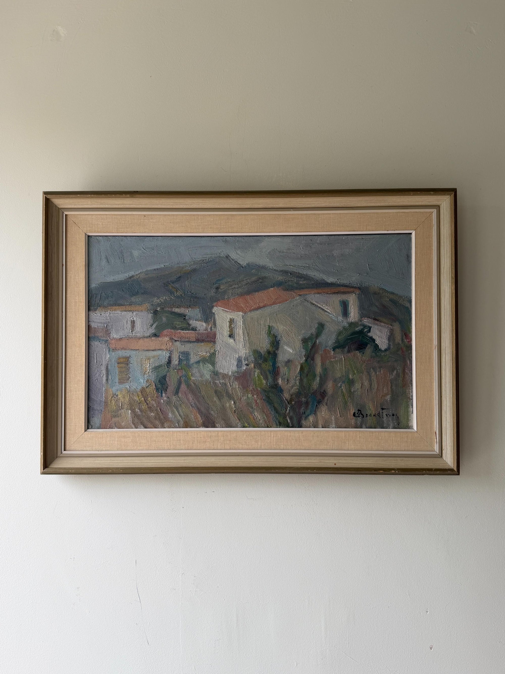 A framed vintage landscape oil painting of a village with mountains in the background. Available at Hue.