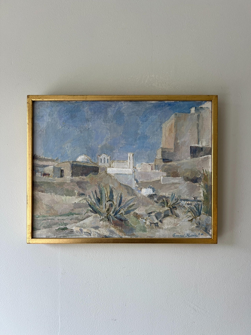 Framed vintage oil painting of a landscape with buildings and blue sky in a slim gilt frame, available at Hue.