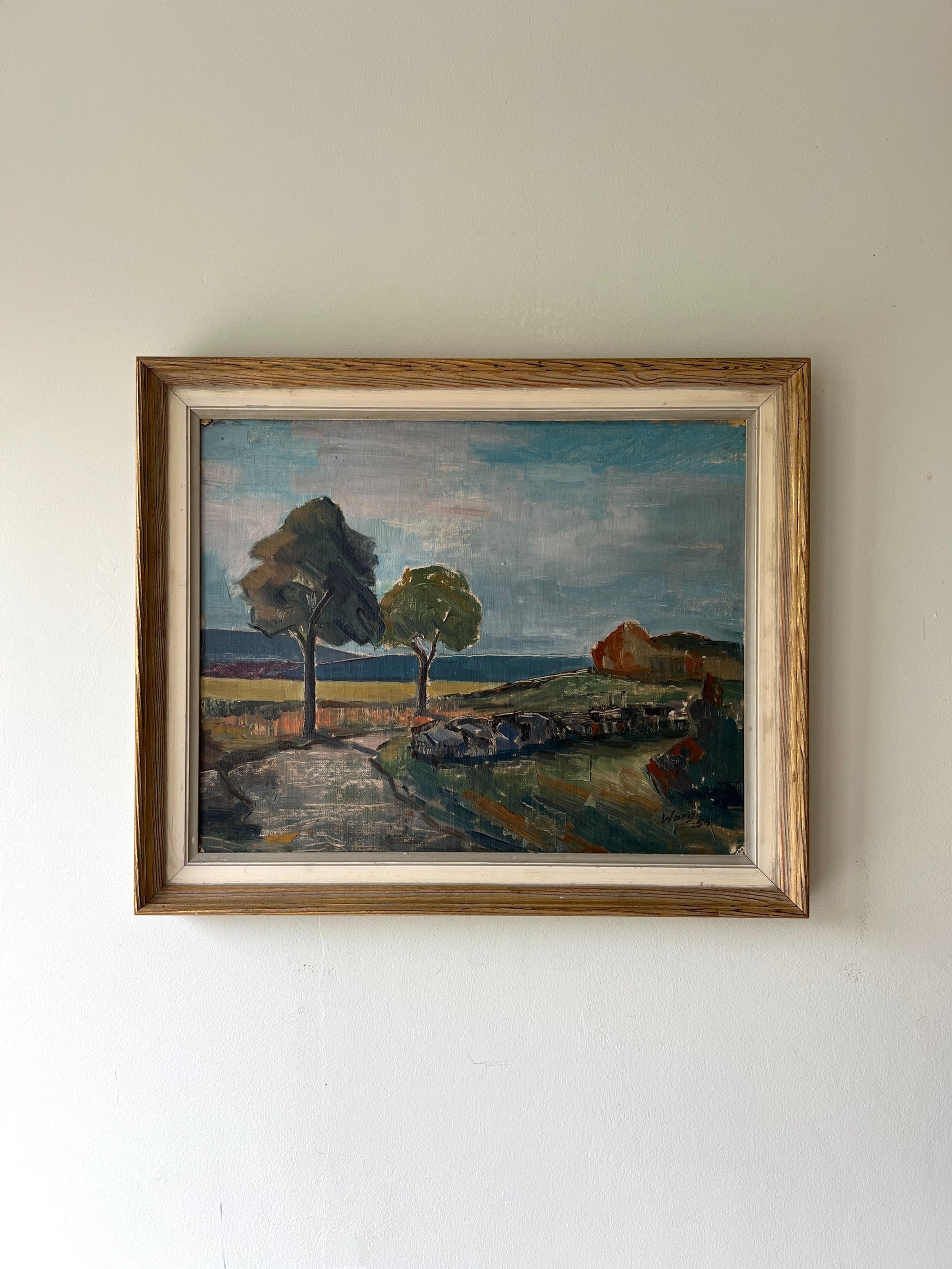 A framed vintage oil painting of a Nordic landscape with a pathway and trees. Available at Hue. 