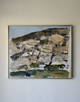 A semi-abstract vintage landscape oil painting in a thin silver frame. The painting features textured brushstrokes of brown, beige, gray, green, and black, depicting a hillside or rocky terrain with sparse trees. Available at Hue.