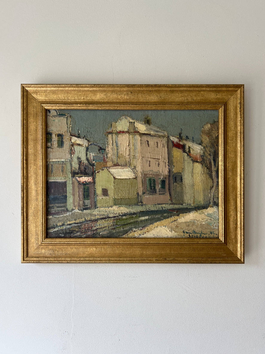Framed vintage oil painting of a street scene with pale house facades. Available at Hue.
