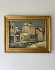 Framed vintage oil painting of a street scene with pale house facades. Available at Hue.