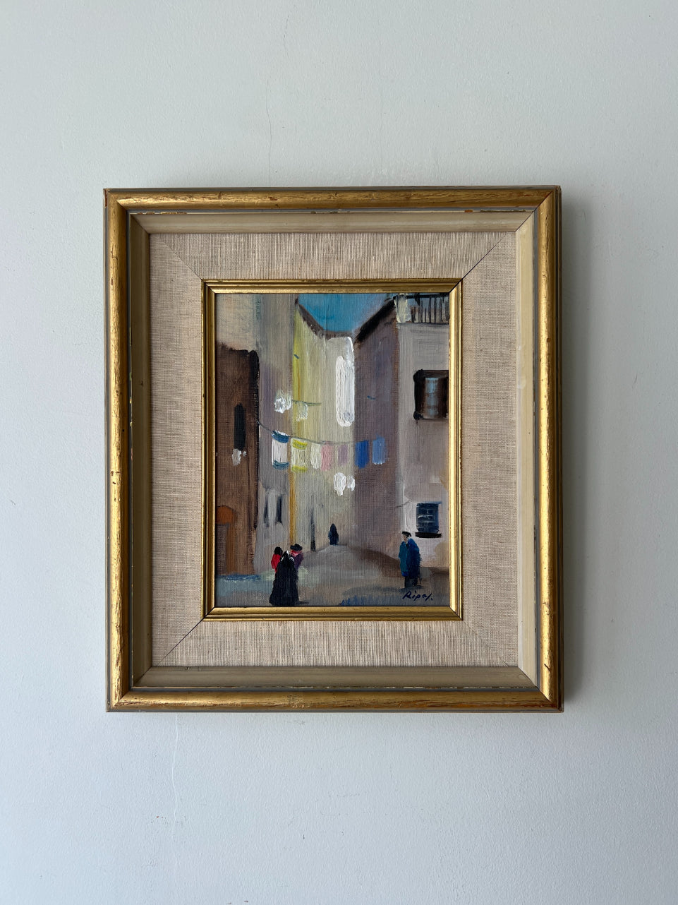 Framed vintage oil painting of an Italian street scene with people and laundry hanging. Available at Hue. 