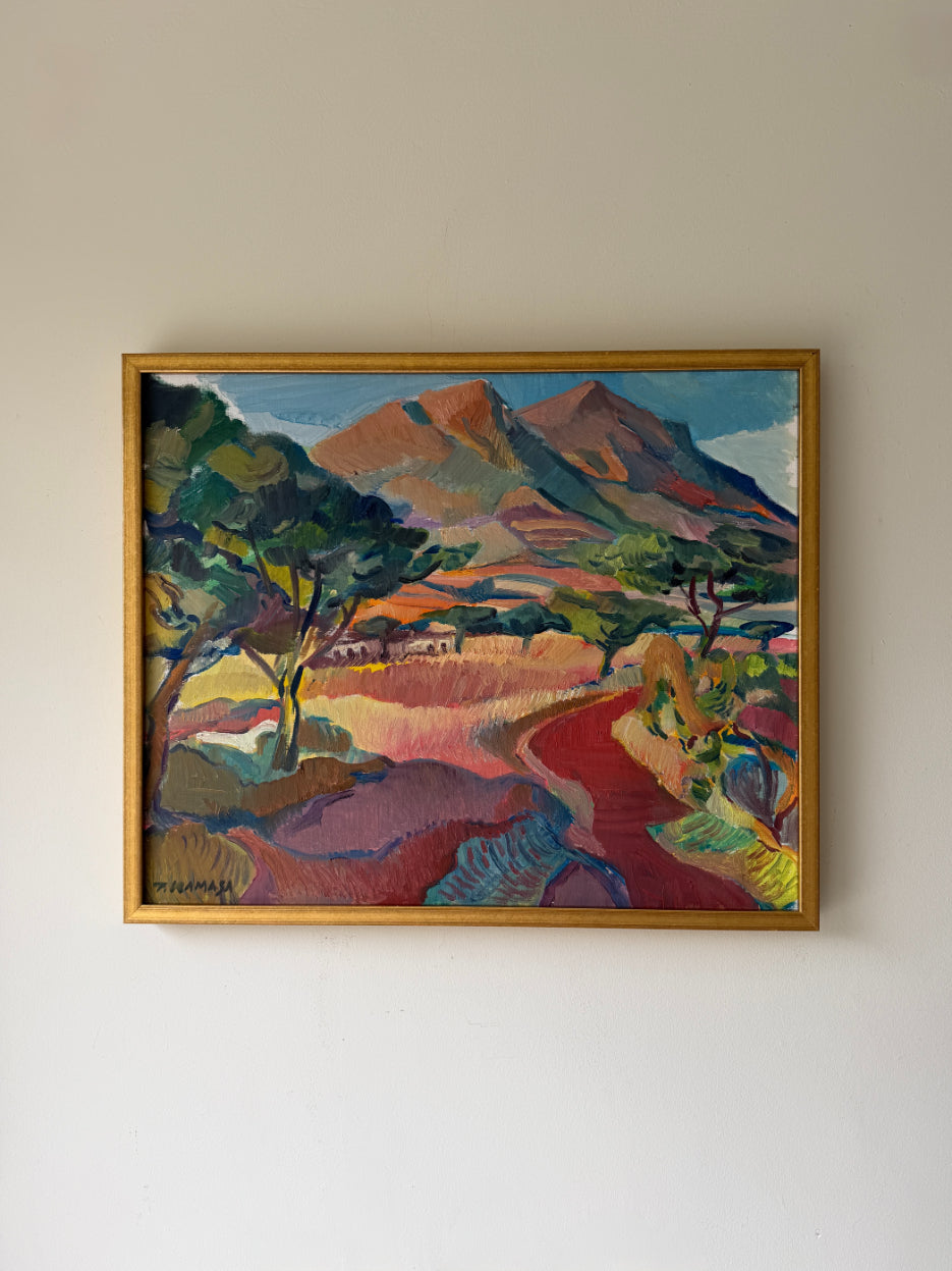 A framed vintage oil landscape painting featuring stylized mountains, trees, and a winding red path. Available at Hue. 