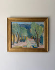 A framed vintage landscape painting depicting a tree-lined path with green foliage, blue hills, and a pale figure in the foreground. Available at Hue. 