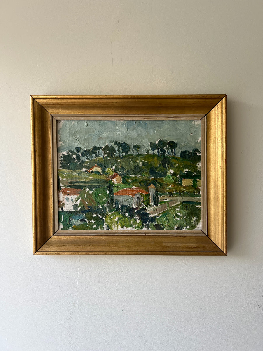 Framed vintage oil painting of a landscape with greenery and a village. Available at Hue. 