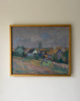 A framed vintage landscape oil painting of a small village with houses, trees, and a cloudy sky. Available at Hue. 
