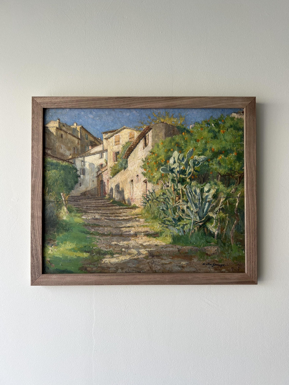 Framed vintage oil painting of a village scene with greenery in a solid walnut frame, available at Hue