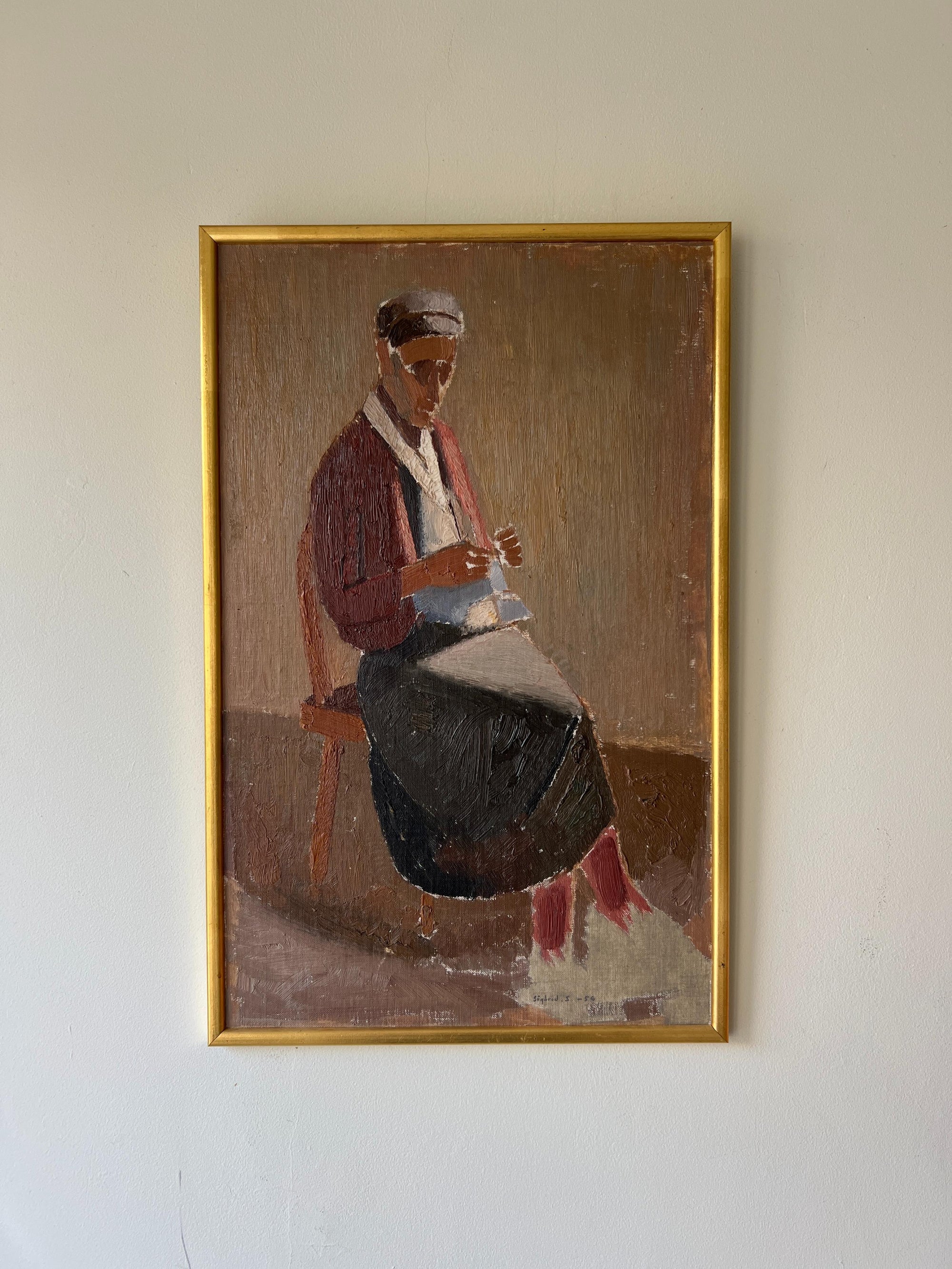 Framed vintage oil painting of a person sitting on a chair, knitting. Gilt frame. Available at Hue.