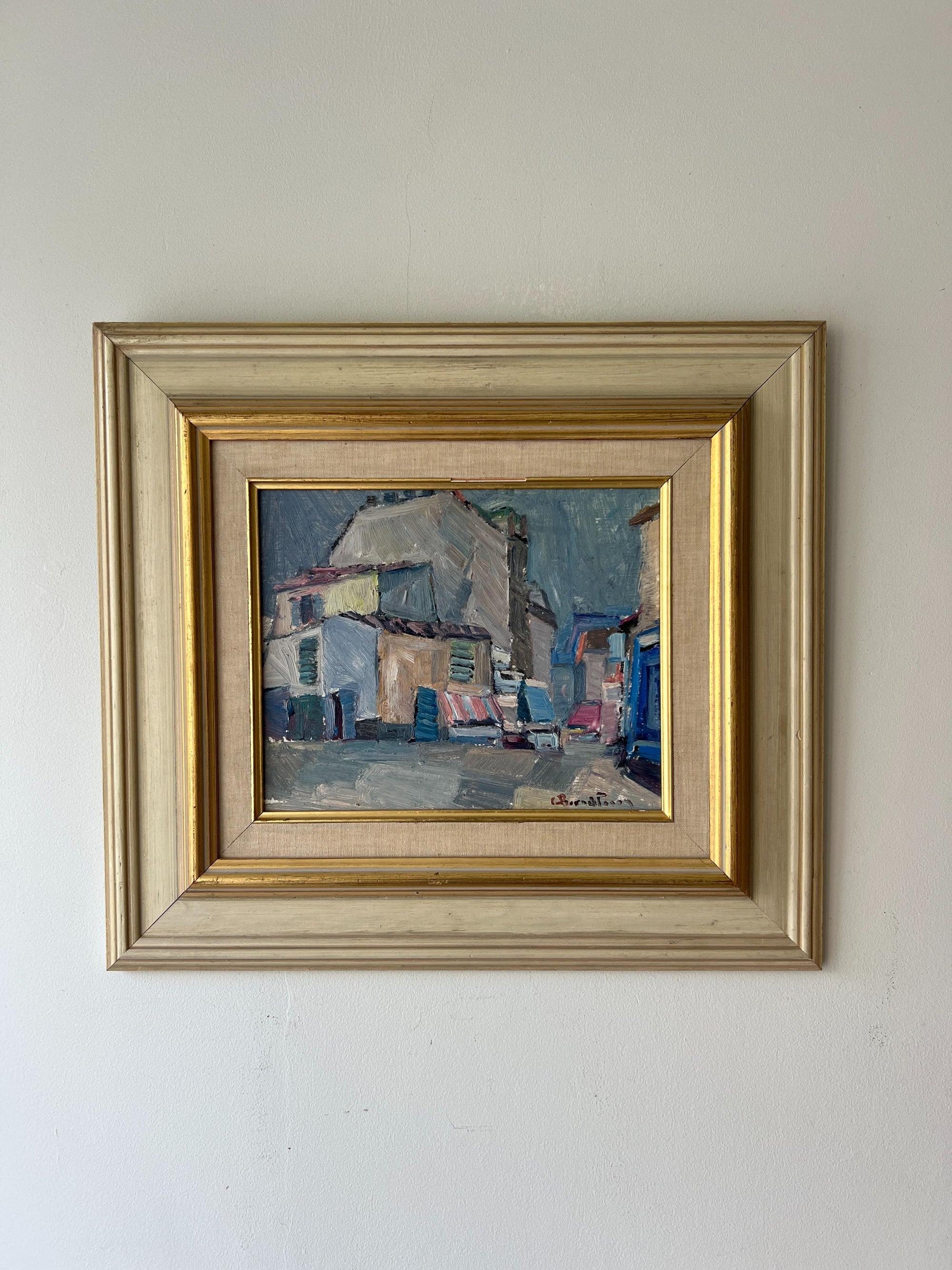 Framed vintage oil painting of a village scene with buildings. Available at Hue.