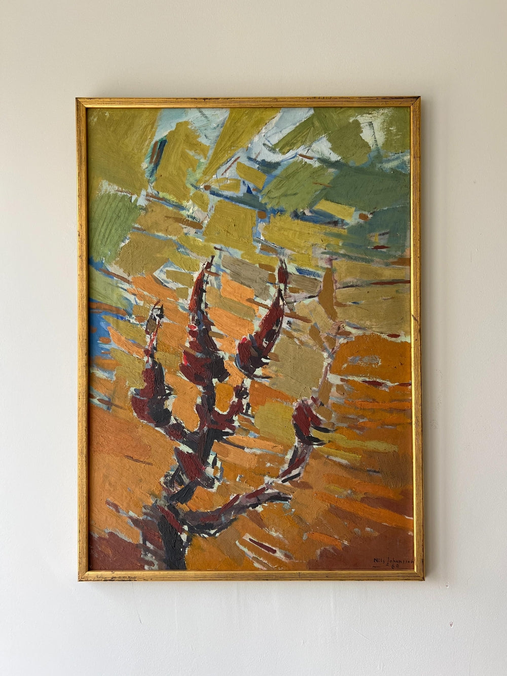 Abstract painting of tree with warm autumnal colors in a gold frame on a beige wall available from hue