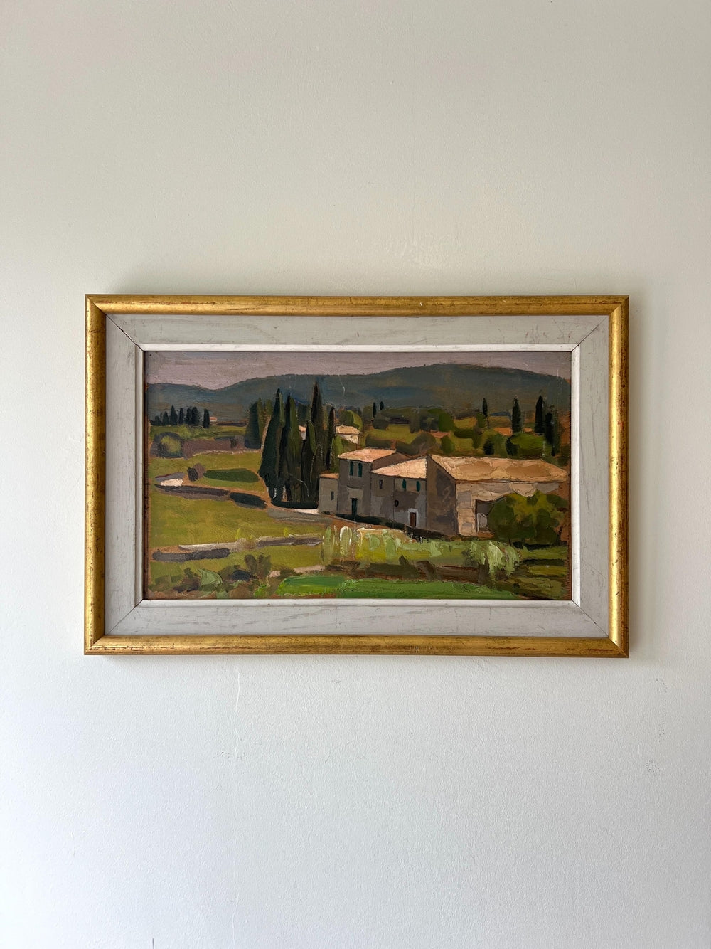 Framed painting of a country green landscape with a farmhouse and trees on a white wall available from hue