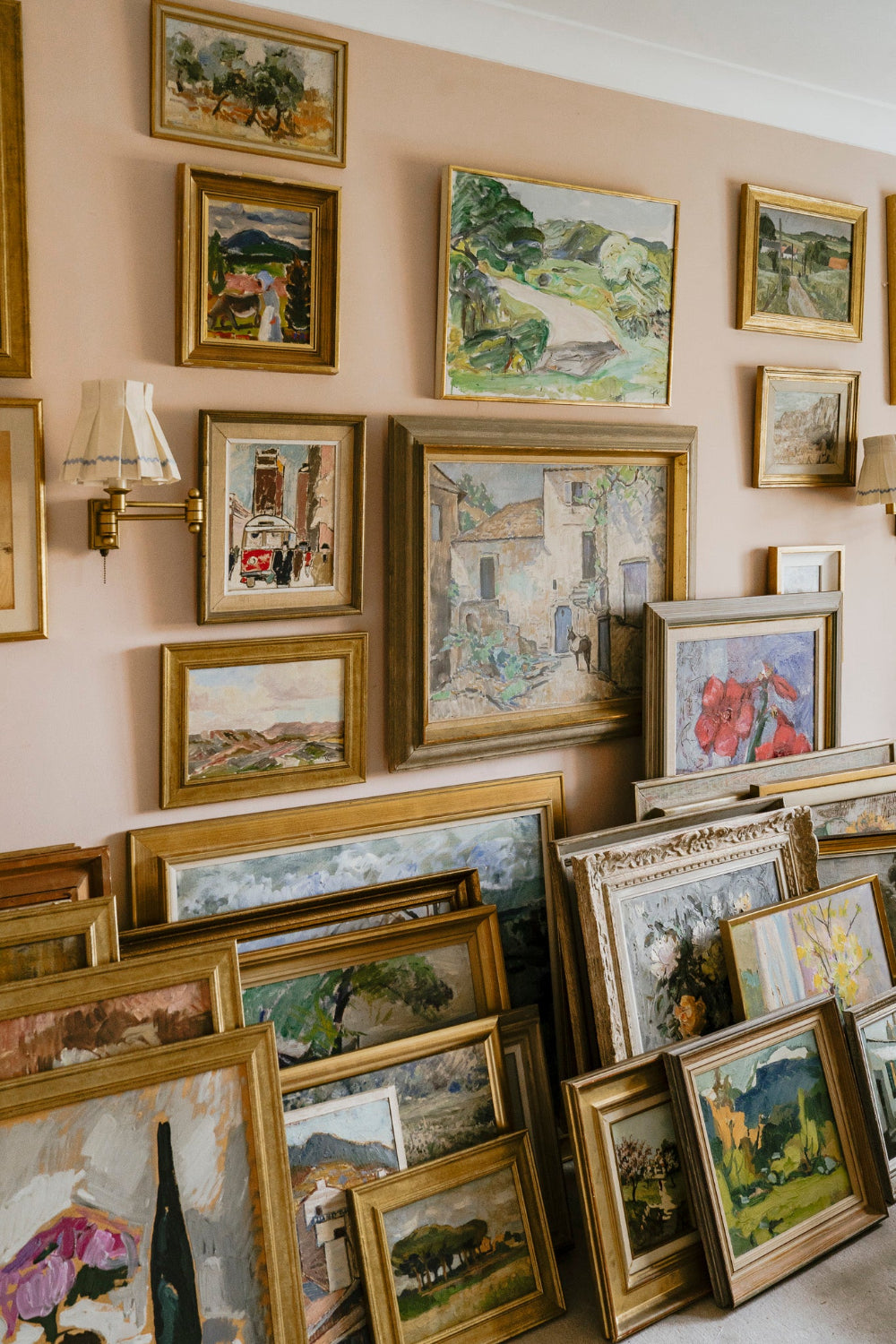 Collection of original vintage art and vintage oil paintings displayed in ornate frames on a gallery wall and floor.