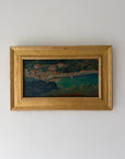 A framed vintage landscape oil painting depicting a coastal town with turquoise water. Available at Hue. 