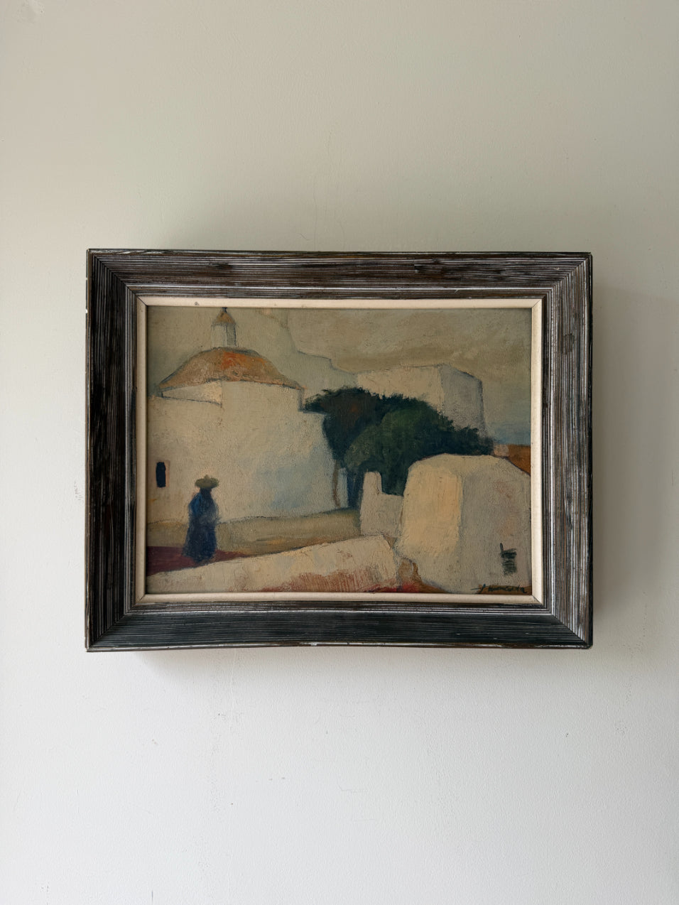 A framed vintage oil painting depicting a Mediterranean-style scene with white buildings, a dark tree, and a small figure. Available at Hue. 