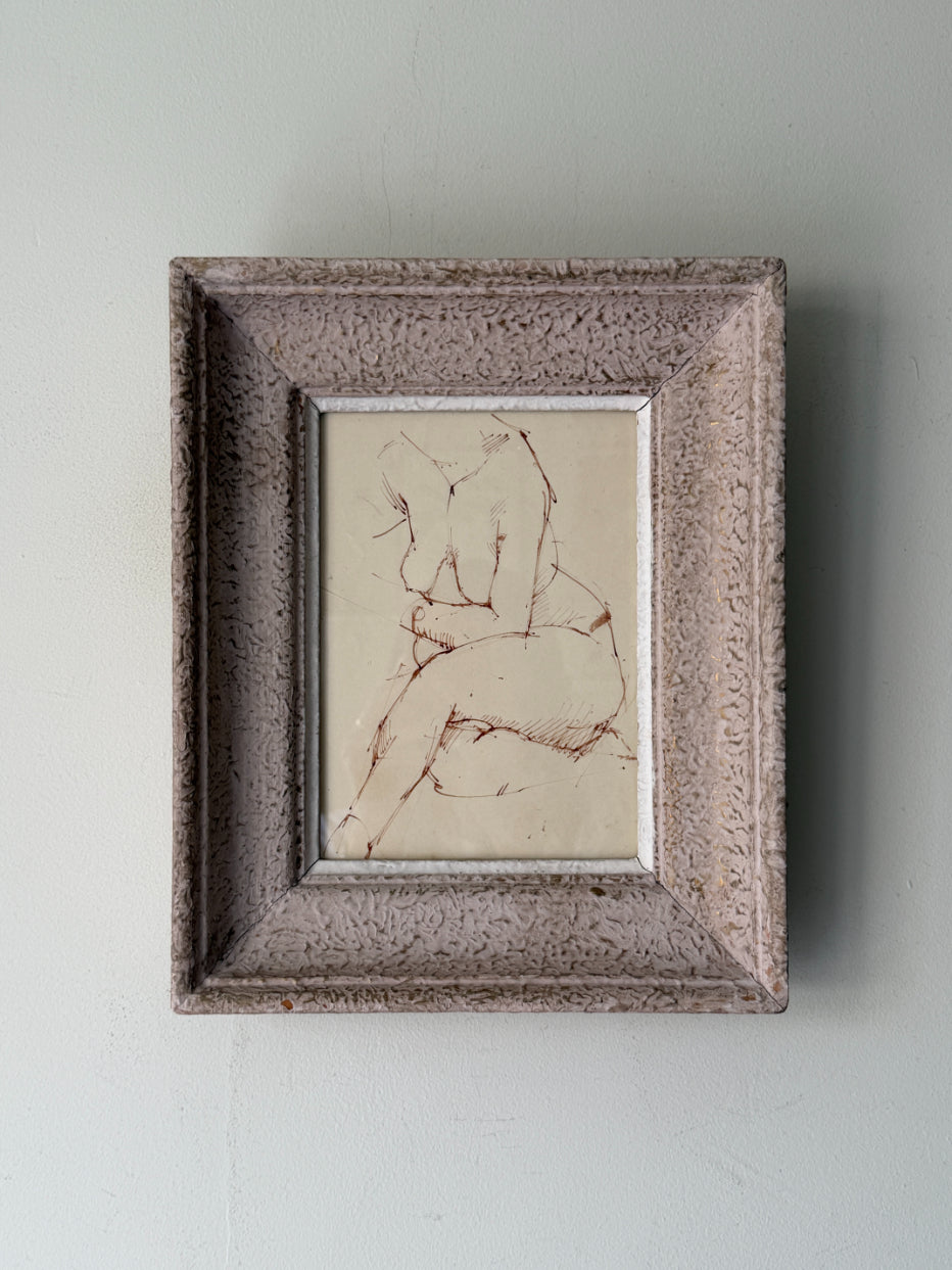 A small vintage framed ink sketch featuring a nude seated figure on a cream background, housed in a rustic, textured gray-brown frame. Available at Hue. 