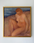 A framed vintage painting of a seated nude woman on a beach, with blue water in the background and a gold frame. Available at Hue.
