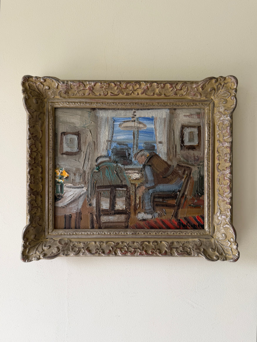 A framed vintage oil painting of two figures sitting at a table in a room, housed in an ornate, carved gold-toned frame. Available at Hue. 
