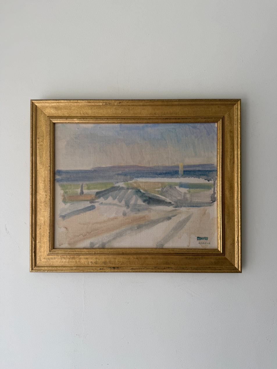 A framed vintage landscape oil painting. The artwork depicts a pale outdoor scene with muted blue, gray, beige, and green tones, enclosed in a gold-toned frame. Available at Hue. 