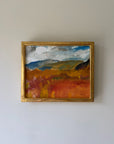 A framed vintage landscape painting featuring a vibrant orange and yellow field under a blue and white cloudy sky, housed in a gold frame. Available at Hue. 
