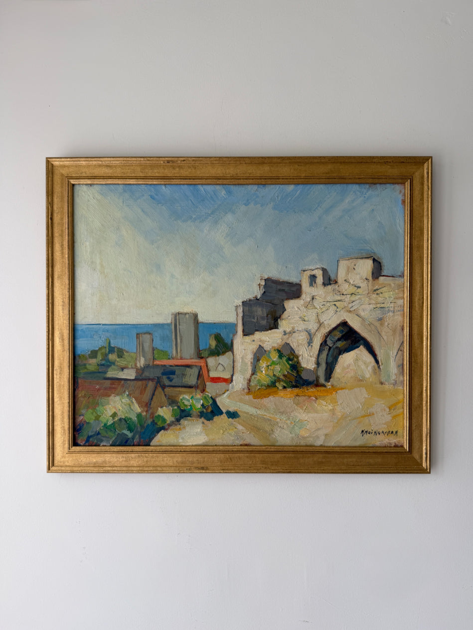 A framed vintage oil painting depicting a coastal landscape with white stone buildings, a blue sea, and a pale sky, housed in a gold-toned frame. Available at Hue. 