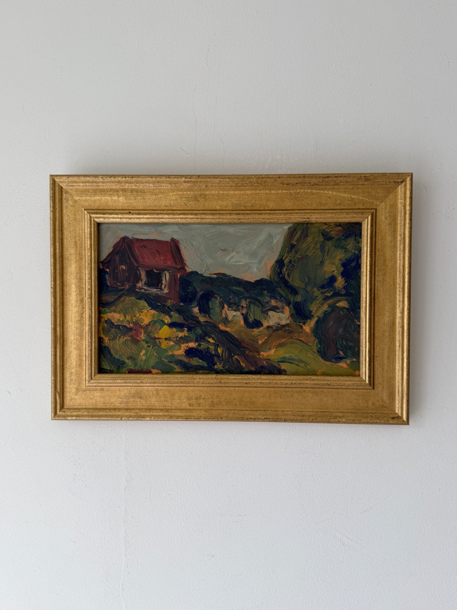 A framed vintage landscape painting featuring a small red-roofed house on a grassy hill, enclosed in a gold frame. Available at Hue. 