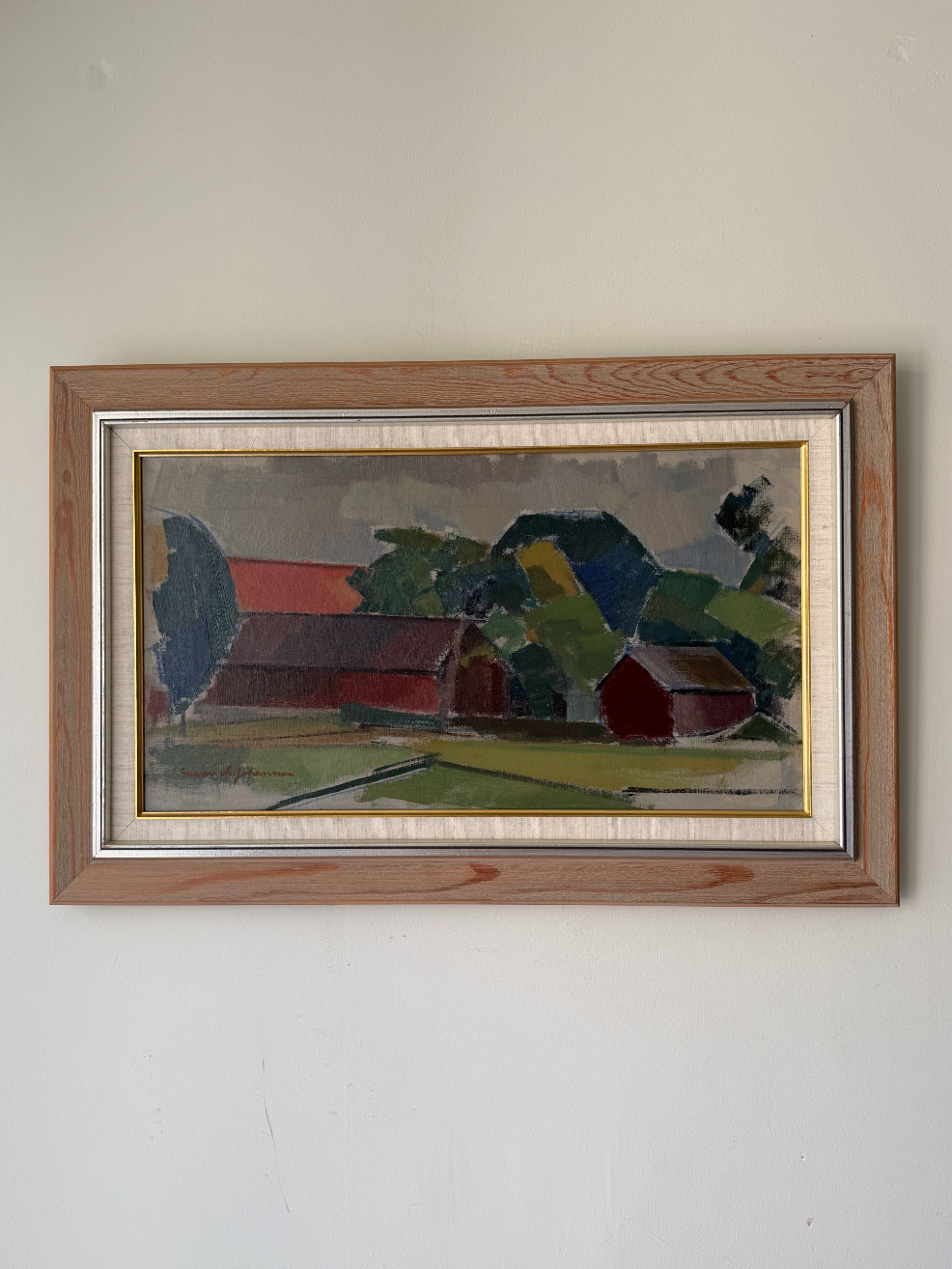 A framed vintage landscape oil painting of a rural scene with red barns, green trees, and a grey sky. Available at Hue.