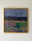 A framed vintage landscape oil painting featuring green fields, dark hills, and a stormy blue-gray sky, enclosed in a thin gold frame. Available at Hue.