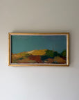 A framed vintage landscape painting. The artwork depicts rolling hills in earthy tones of green, yellow, brown, and red under a deep teal-blue sky, enclosed in a thin vintage gold frame. Available at Hue. 