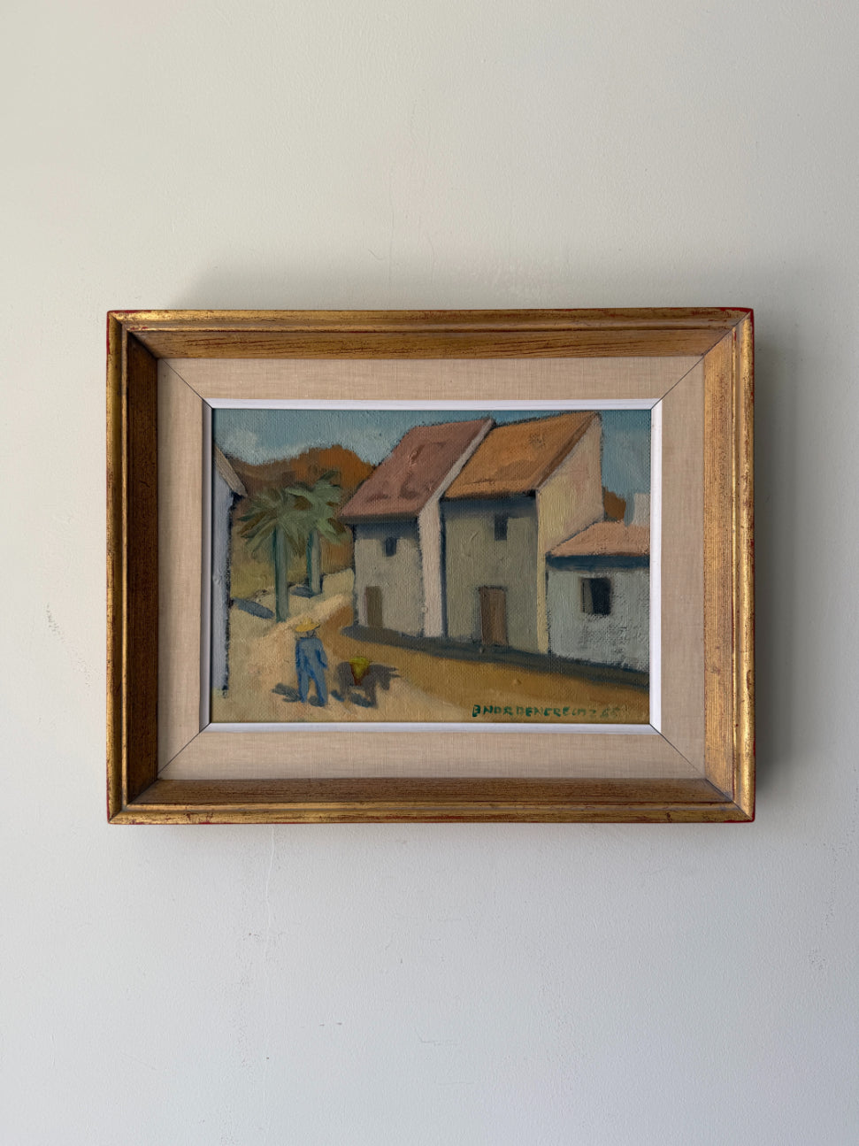 A framed vintage oil painting depicting a quiet village street with white buildings, terracotta roofs, and a palm tree. Available at Hue. 