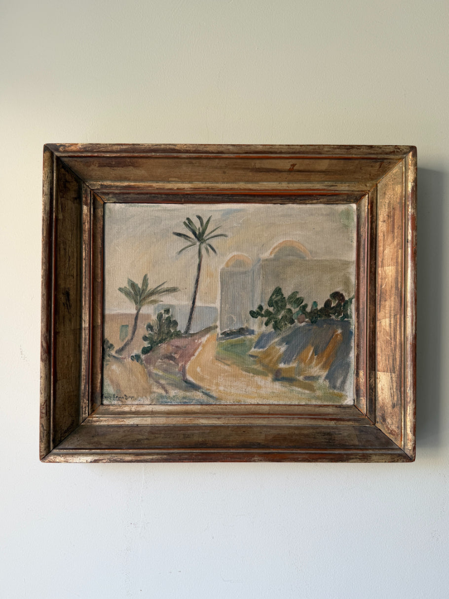 A framed vintage landscape oil painting featuring palm trees, hills, and arches, housed in a rustic dark brown wooden frame. Available at Hue. 