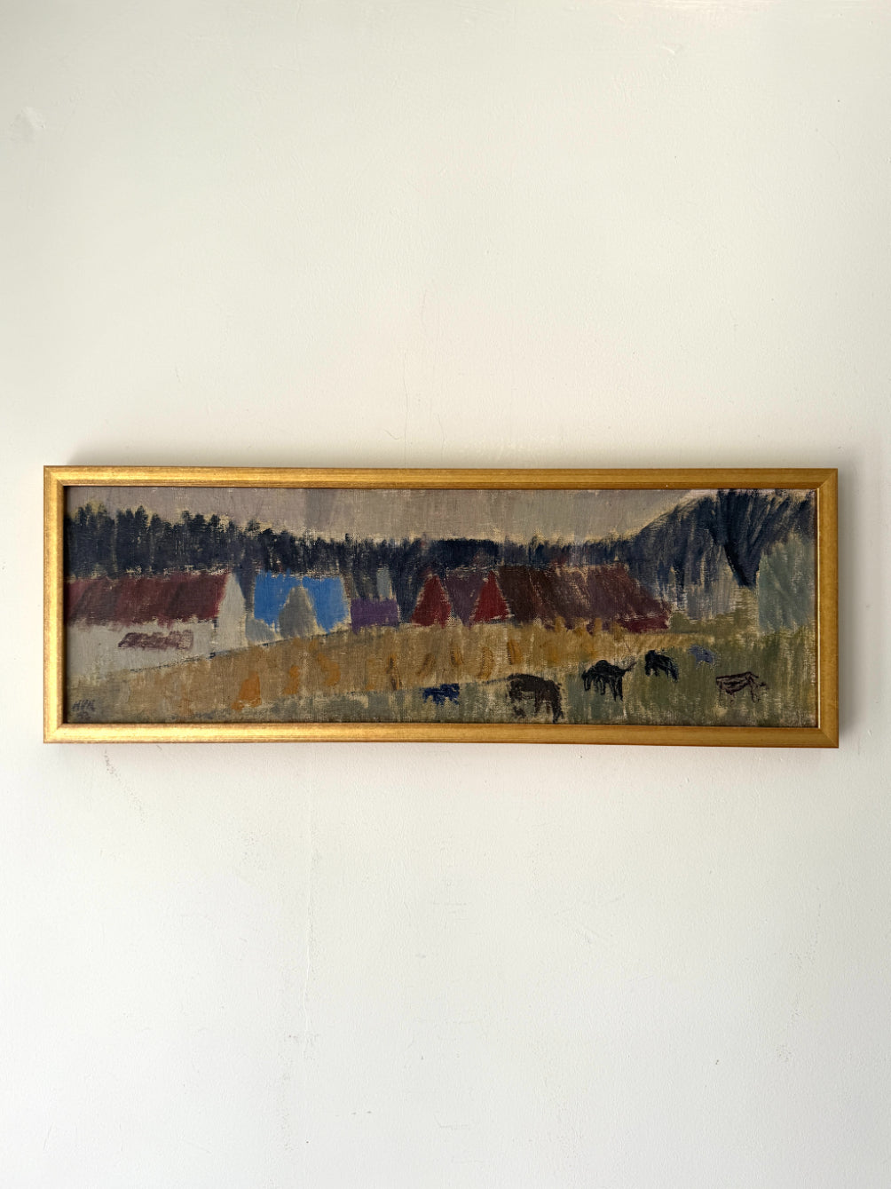 A framed vintage landscape painting featuring stylized houses, trees, and grazing horses, housed in a gold frame. Available at Hue.