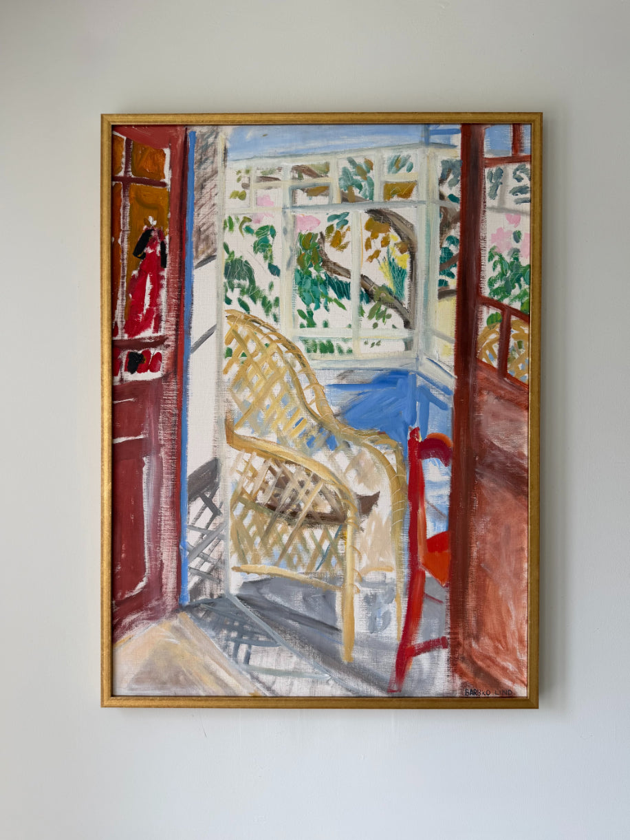 A framed vintage painting depicting a sunlit interior scene with a wicker chair, red doorframes. Available at Hue. 