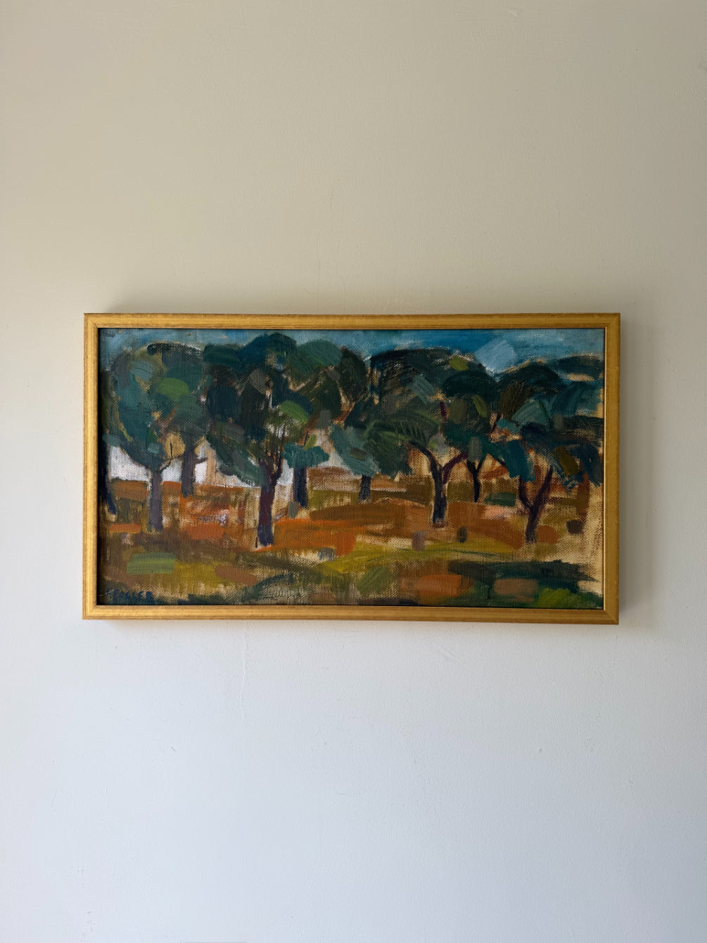A framed vintage landscape painting featuring dark green trees and a brown ground. Available at Hue. 