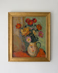 A framed vintage oil painting of a floral bouquet in a ceramic pitcher. The painting features a variety of colorful flowers including red, orange, yellow, and pink, set against a muted green background. Available at Hue.