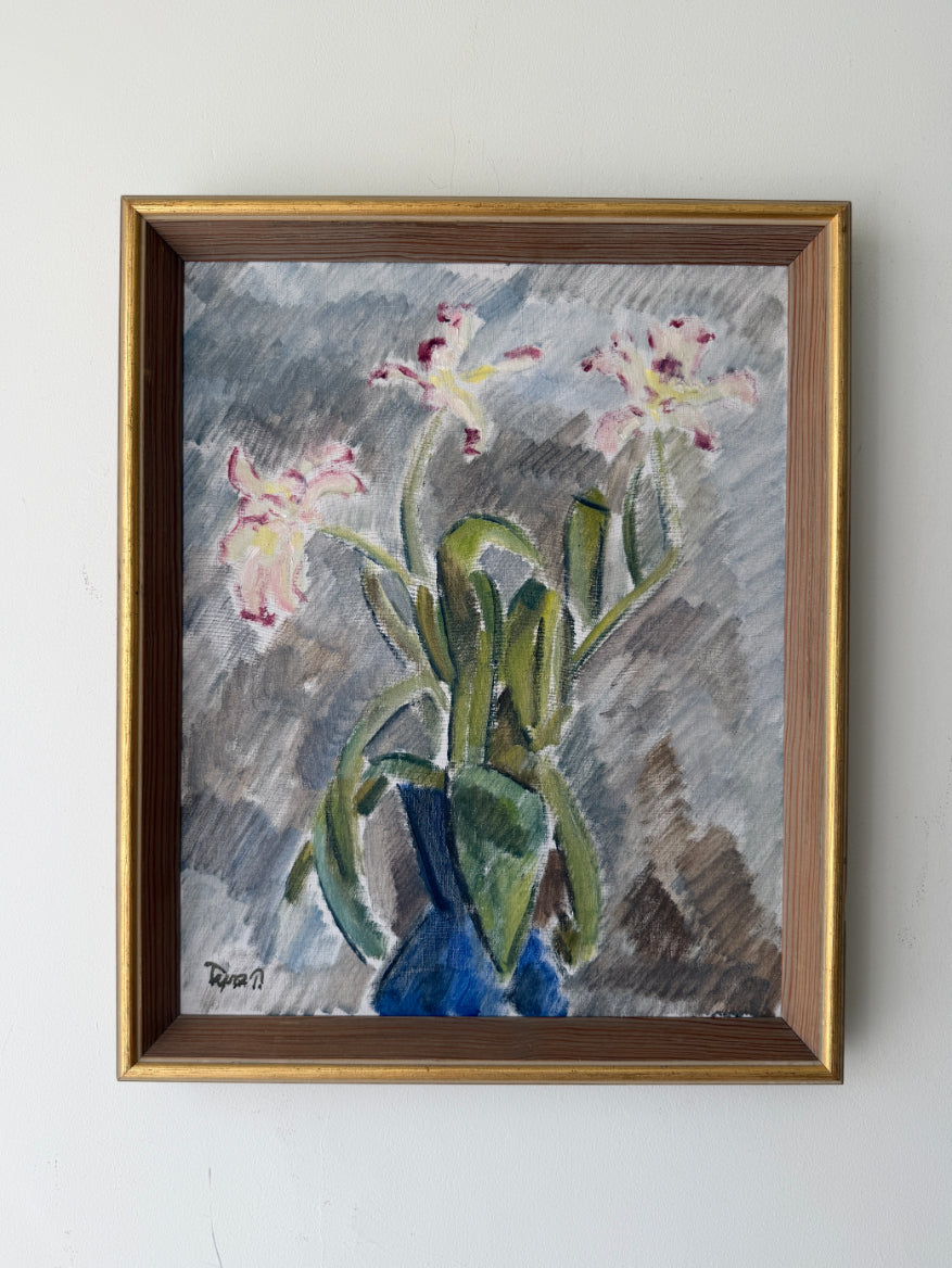 A framed vintage still life painting of pink and white flowers with green leaves in a blue vase, enclosed in a gold-toned wooden frame. Available at Hue. 