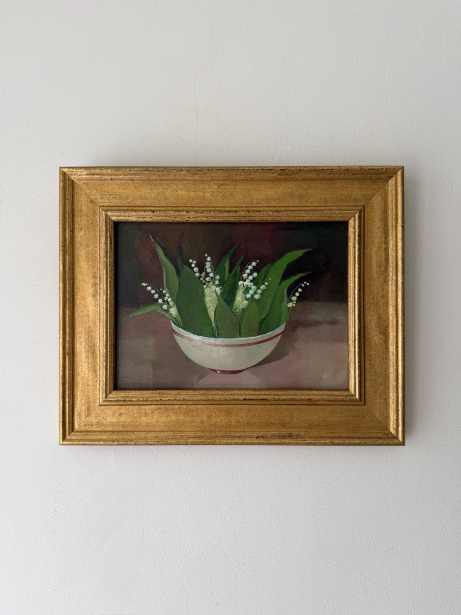 A framed vintage still life painting of lily of the valley flowers in a white bowl with green leaves. Available at Hue. 