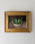A framed vintage still life painting of lily of the valley flowers in a white bowl with green leaves. Available at Hue. 