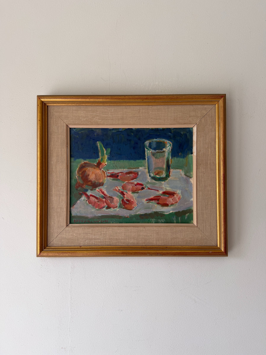 A framed vintage still life painting depicting a glass, an onion, and several cooked prawns on a white cloth against a dark blue background. The artwork is housed in a gold-toned frame. Available at Hue. 