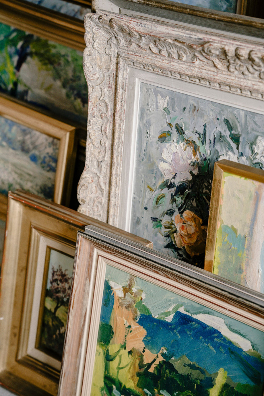 Layered collection of original vintage floral and landscape oil paintings in decorative antique and gilt frames from the Hue + Holasz art collection.